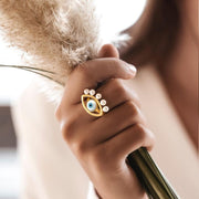 femme portant une bague mauvais oeil dorée avec des perles tenant dans la main des fleurs de pampas 
